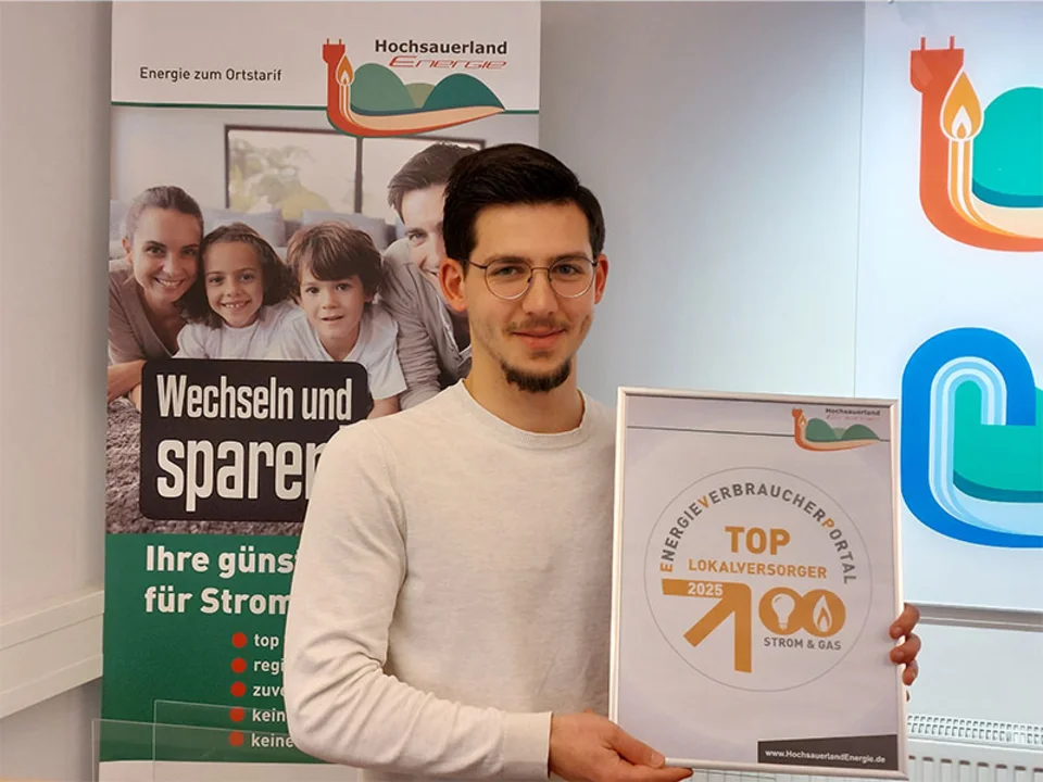 HE-Mitarbeiter Marcelo Costa Rebelo präsentiert das Qualitätssiegel: Die HochsauerlandEnergie GmbH ist als „Top-Lokalversorger Strom & Gas 2025“ ausgezeichnet worden.
